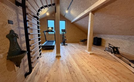 Dachboden-Fitnessraum mit Holzfußboden, Sprossenwand, Laufband, Fahrradtrainer und Rudergerät