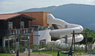 Riesige weiße Rutsche, die an einem modernen Haus mit Holzverkleidung und Balkon angebracht ist