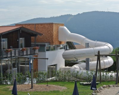 Riesige weiße Rutsche, die an einem modernen Haus mit Holzverkleidung und Balkon angebracht ist