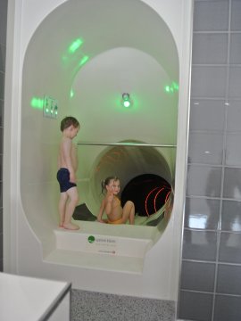 Zwei Kinder in Badebekleidung an einem Wasserrutschen-Eingang mit grüner Lampe
