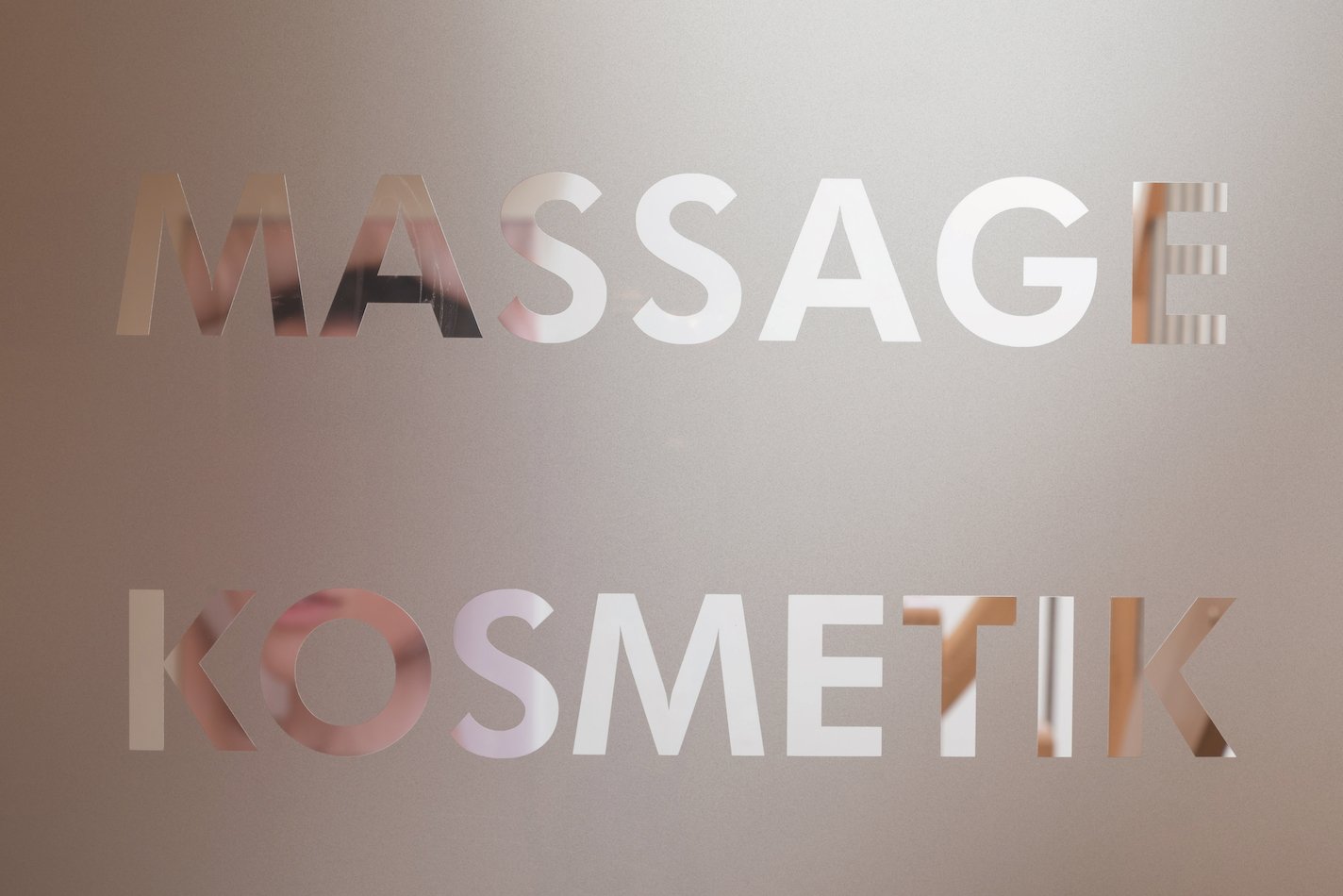 Glas mit ausgeschnittenen Buchstaben Massage Kosmetik vor unscharfem Hintergrund