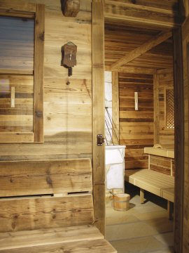 Holzsauna mit Holzbänken, Kuckucksuhr an der Wand und Holzeimer auf dem Boden