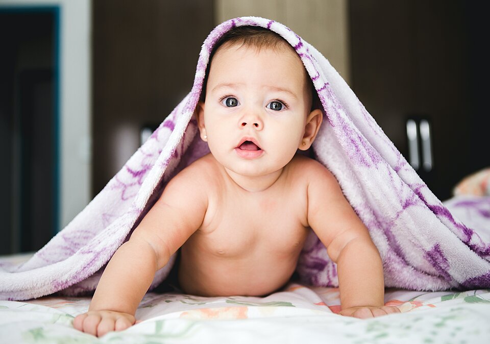 Baby schaut unter Decke hervor