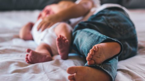 Nahaufnahme von zwei Kindern, die nebeneinander auf einem Bett liegen, Fokus auf den Füßen