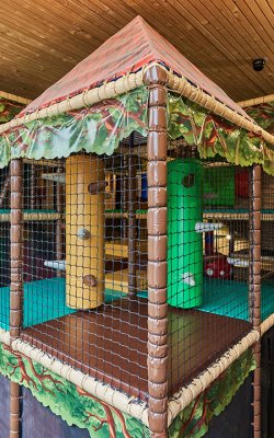 Innenansicht eines mehrstöckigen, netzumsponnenen Klettergerüsts mit Holzdecke und Holzwänden