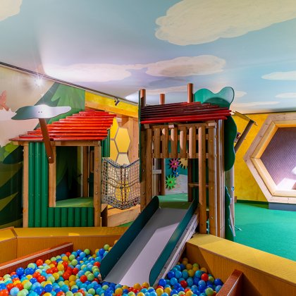 Bunter Indoor-Spielplatz mit Rutsche, Ballbecken und gemütlicher Sitzecke in Wabenform