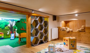 Kinderspielzimmer mit Holzregal, Spielwürfeln auf Teppich und Kuschelbären in Holznische