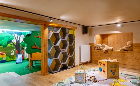 Kinderspielzimmer mit Holzregal, Spielwürfeln auf Teppich und Kuschelbären in Holznische