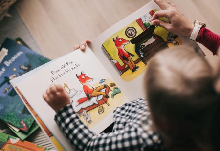 Kind liest ein Bilderbuch mit einem Fuchs, der seine Socken verloren hat