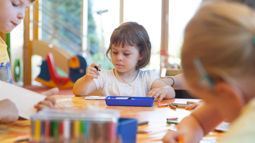 Drei kleine Kinder spielen am Laufrad