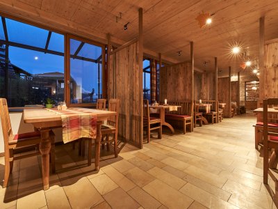 Innenraum eines Restaurants mit Holztischen, Stühlen und Trennwänden, abends mit Kerzenlicht
