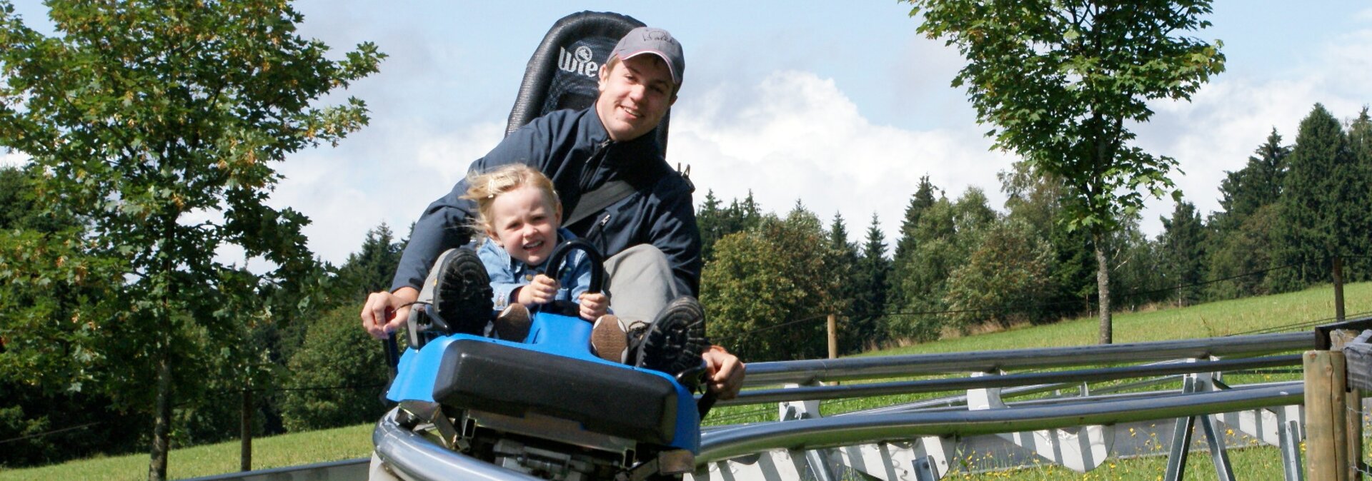 Vater mit Tochter auf der Sommerrodelbahn