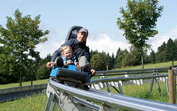 Vater mit Tochter auf der Sommerrodelbahn