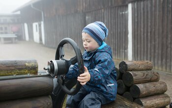 Junge sitzt auf einem Holztraktor