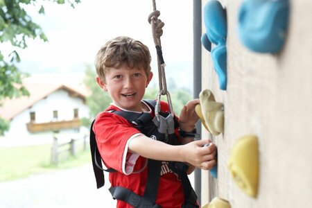 Junge klettert auf hauseigener Kletterwand