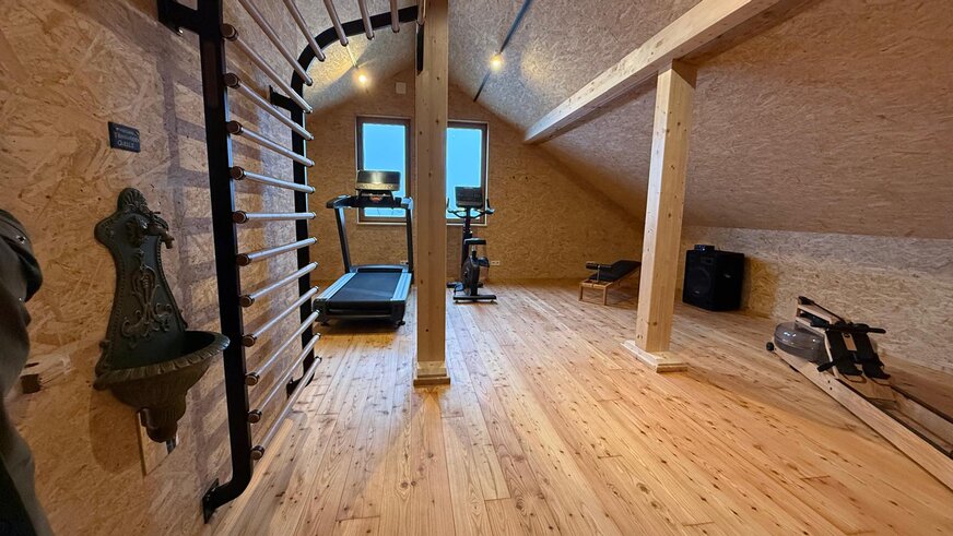 Einblick in den Fitnessraum aus Holz mit vielen Fitnessgeräten