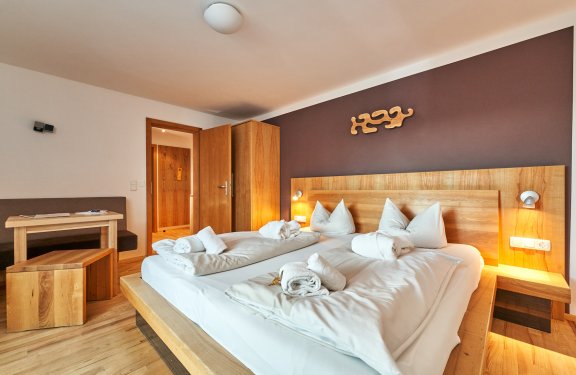Hell eingerichtetes Schlafzimmer mit großem Bett, Holzmöbeln und offenem Türrahmen