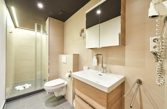 Modernes Badezimmer mit Dusche links, Toilette in der Mitte und Waschbecken mit Spiegel rechts