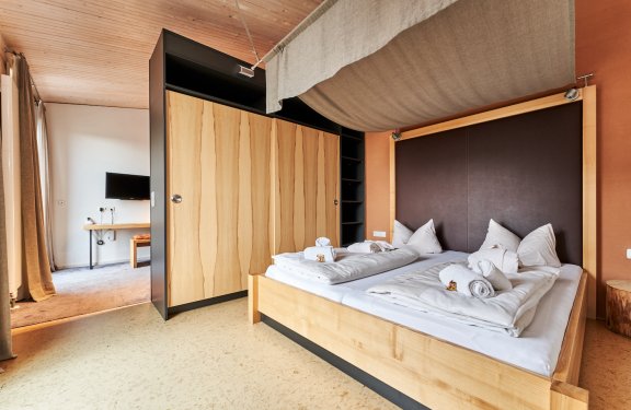 Helles Schlafzimmer mit Holzbettrahmen, weißen Bettdecken und Schrank mit Holzfront