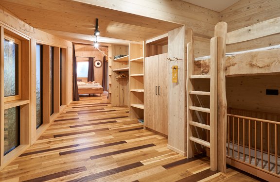 Flur mit Holzregalen, Kleiderschrank, Etagenbett und Fenster links, Schlafzimmer im Hintergrund
